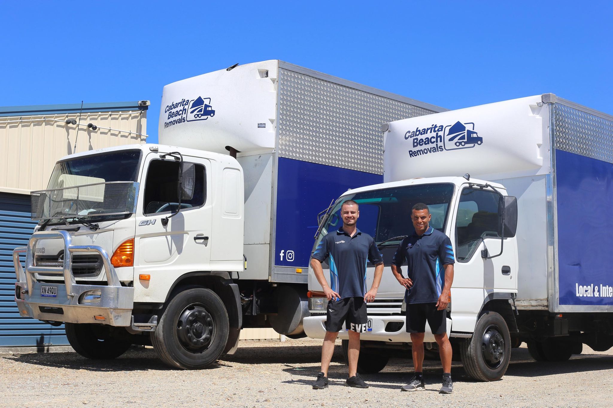 Two Men Standing Before Two Trucks