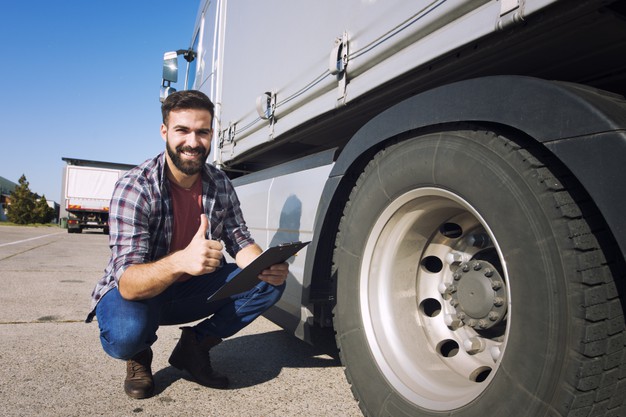 A Man Checking Truck Tires With a Pad